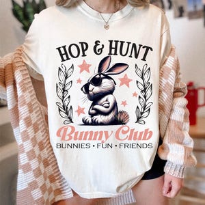 May include: White t-shirt with a pink bunny wearing sunglasses and the text "Hop & Hunt Bunny Club Bunnies Fun Friends".