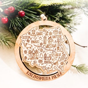 May include: A wooden ornament shaped like the outline of Poland with the names of major cities and the text "RZECZPOSPOLITA POLSKA" inscribed on the bottom.