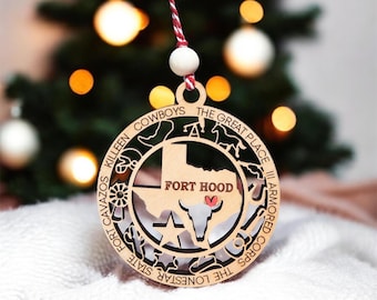 Könnte beinhalten: Ein kreisförmiger Holzschmuck mit einer ausgeschnittenen Karte von Texas, dem Text FORT HOOD und einem kleinen roten Herz. Der Rand enthält den Text KILLEEN COWBOYS THE GREAT PLACE III ARMORED CORPS THE LONESTAR STATE FORT CAVAZOS und Symbole.