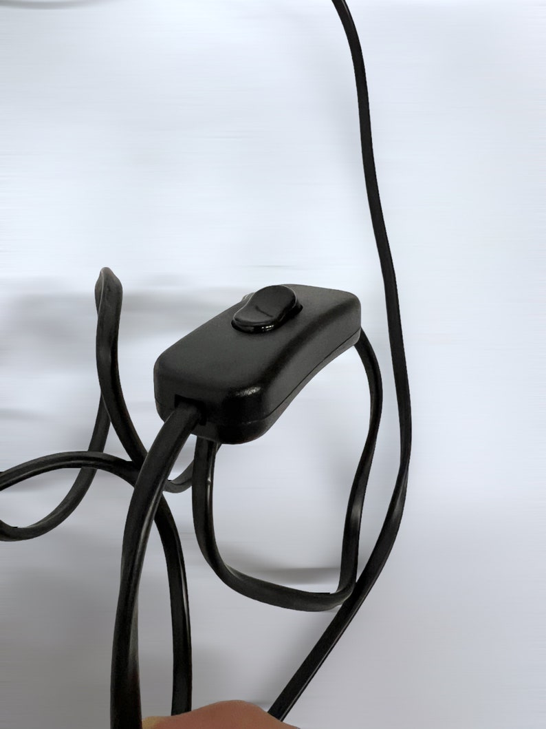 Może przedstawiać: Czarny przew&oacute;d elektryczny z wbudowanym włącznikiem/wyłącznikiem.