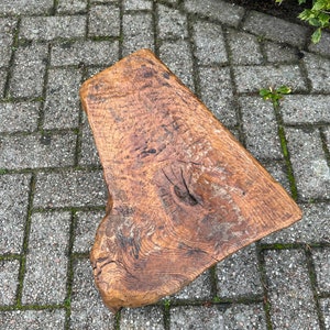 Puede incluir: Un taburete de madera r&uacute;stico con una forma natural irregular y un acabado marr&oacute;n oscuro. El taburete est&aacute; hecho de una sola pieza de madera y tiene un aspecto &uacute;nico hecho a mano.