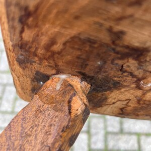 Puede incluir: Primer plano de una pata de silla de madera con un acabado marr&oacute;n claro. La pata est&aacute; unida al asiento de la silla con una junta de madera. Se puede ver una peque&ntilde;a cantidad de pegamento blanco en la junta.