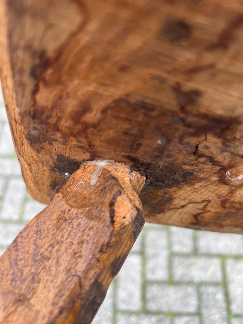 Puede incluir: Primer plano de una pata de silla de madera con un acabado marr&oacute;n claro. La pata est&aacute; unida al asiento de la silla con una junta de madera. Se puede ver una peque&ntilde;a cantidad de pegamento blanco en la junta.