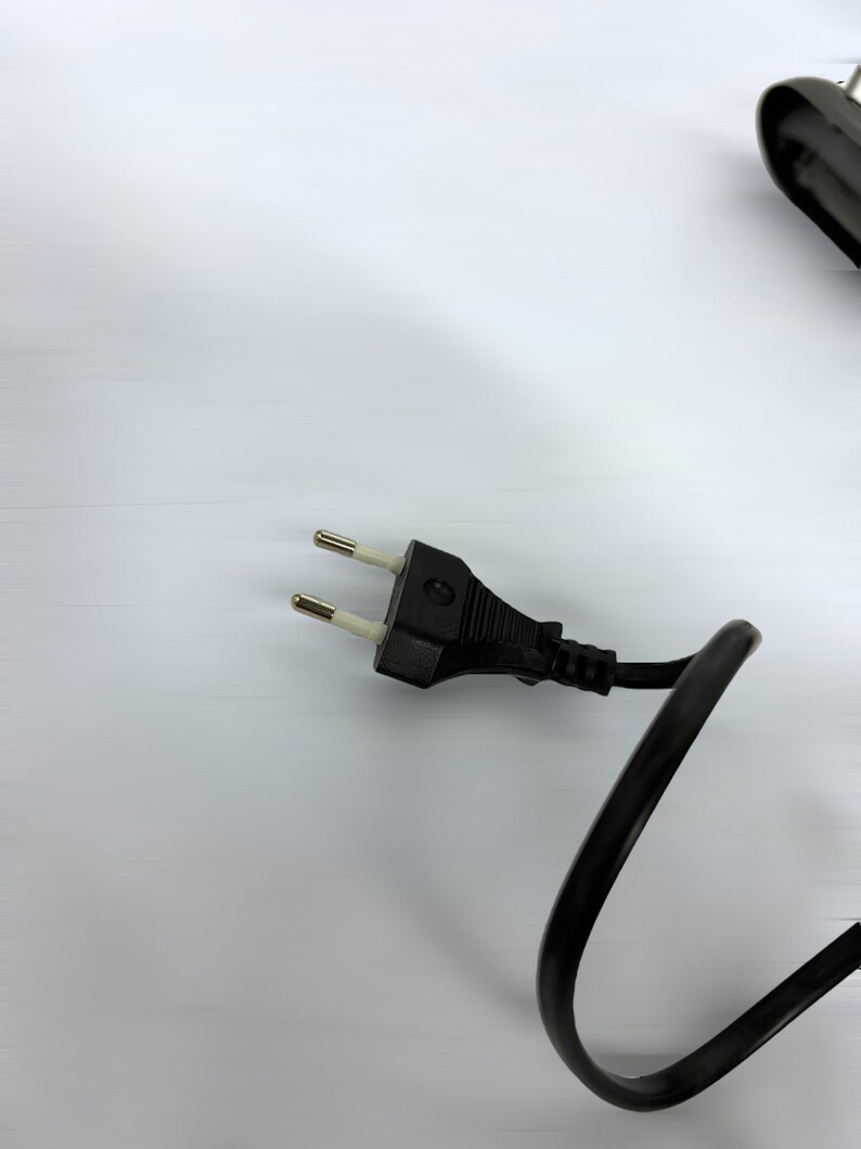 Może przedstawiać: Czarny przew&oacute;d elektryczny z wtyczką europejską z dwoma bolcami.