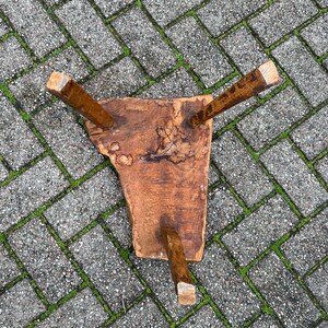 Puede incluir: Un taburete de madera r&uacute;stico con tres patas. El taburete est&aacute; hecho de una sola pieza de madera y tiene un acabado natural sin tratar.