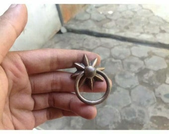 Könnte beinhalten: Ein Messing-Ringzug mit sternförmigem Design. Der Ring ist glatt und hat eine leicht gealterte Oberfläche.