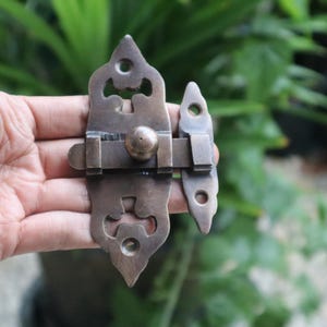 Könnte beinhalten: Ein Messingriegel mit einem verzierten Design. Der Riegel hat einen dekorativen Griff und einen Verriegelungsmechanismus.