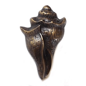 Può includere: Una manopola per porta a forma di conchiglia, di colore bronzo, con una superficie testurizzata.