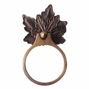 May include: A brass ring door pull with a decorative leaf design. The ring is round and the leaves are detailed and textured.