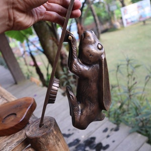 May include: A bronze rabbit door knocker with a detailed design. The rabbit is standing on its hind legs with its front paws raised. The knocker is attached to a metal plate.
