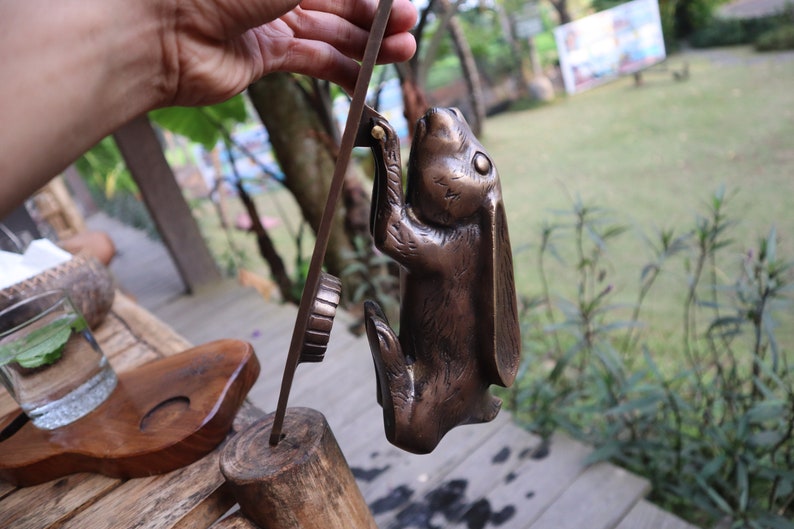 May include: A bronze rabbit door knocker with a detailed design. The rabbit is standing on its hind legs with its front paws raised. The knocker is attached to a metal plate.