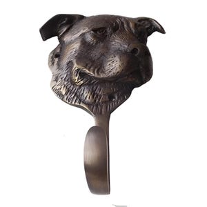 May include: A brass coat hook shaped like a Staffordshire Bull Terrier dog's head. The hook is antique brass in color and has a detailed design.