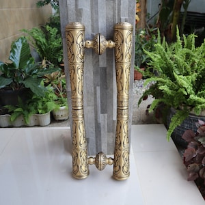 May include: A pair of ornate gold door handles with intricate designs. The handles are made of metal and have a polished finish.