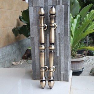 May include: Two antique gold door handles with ornate designs and pointed tips.