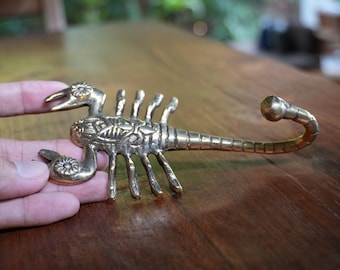 May include: A brass scorpion hook with intricate details. The scorpion's tail is curled into a hook shape.