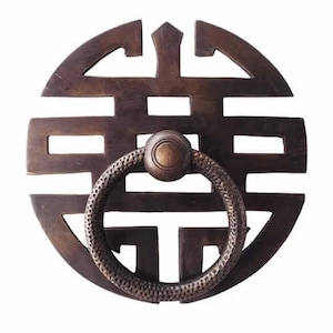 Könnte beinhalten: Ein runder Türklopfer aus Messing mit einem Ringgriff und einem traditionellen chinesischen Symbolmuster.