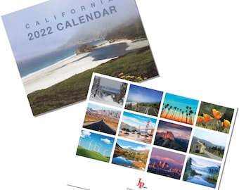 May include: A 2022 California calendar featuring scenic photos of the state. The cover image shows a beach with a bay and a mountain in the background. The calendar is printed by JP Prints.