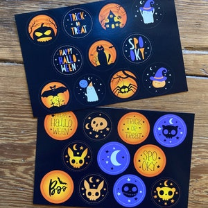 May include: Two sheets of black and orange Halloween stickers with various designs. The stickers include a ghost, a spider, a pumpkin, a house, a cat, a bat, and the text "Trick or Treat", "Spooky", and "Happy Hallo Ween".