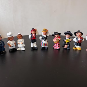 May include: A set of miniature painted figurines representing different occupations and traditional dress. The figurines include a sailor, chef, nurse, and figures in folk costumes, each with unique details and colours.