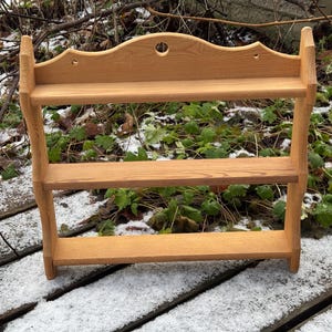 May include: A wooden shelf with two shelves. The shelf is made of natural wood and has a simple design. It is perfect for displaying small items or organising a kitchen.