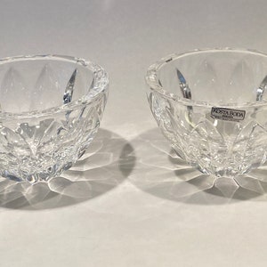 Puede incluir: Dos cuencos de cristal transparente con un patrón de corte de diamante. Los cuencos son redondos con un borde ligeramente inclinado. Los cuencos están hechos de cristal transparente y probablemente sean para servir o exhibir. Los cuencos están sobre una superficie blanca.