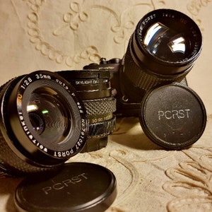 May include: Three black camera lenses with the brand name "PORST" printed on them. The lenses are all different sizes and have different markings on them.