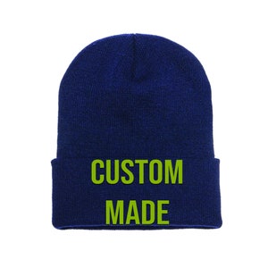 May include: A navy blue beanie with the words "CUSTOM MADE" in lime green lettering.