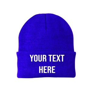 May include: A royal blue beanie with the text "YOUR TEXT HERE" in white.