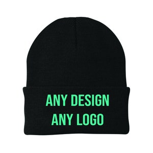 May include: Black knitted beanie with a fold-over cuff. The beanie has the text "ANY DESIGN ANY LOGO" in green.