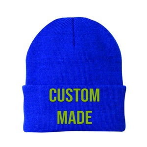 May include: A blue knitted beanie with the words "CUSTOM MADE" in green lettering.