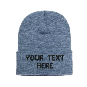 May include: A blue knit beanie with the text "YOUR TEXT HERE" embroidered in black.