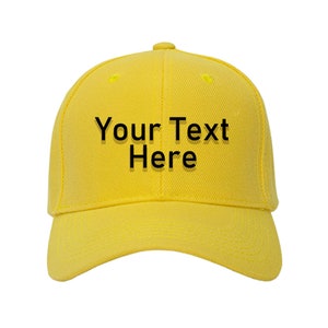 Op de afbeelding: Een gele baseballpet met zwarte tekst die "Your Text Here" zegt.