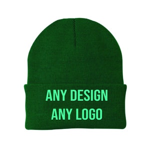 Puede incluir: Un gorro de lana verde oscuro con el texto "ANY DESIGN ANY LOGO" en verde claro.