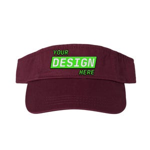 May include: A maroon visor with the text "YOUR DESIGN HERE" in green and white. The visor is made of a soft material and has a curved brim to shield the eyes from the sun. The text is centered on the front.