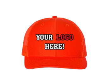 May include: Bright orange trucker hat with the text "YOUR LOGO HERE!" in white and red. The hat features a mesh back and a curved brim, suitable for outdoor activities or casual wear.