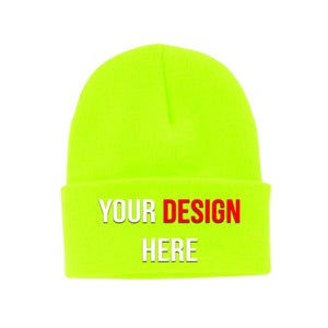 May include: A neon green beanie hat with a folded brim. The text "YOUR DESIGN HERE" is printed across the brim in white and red. The hat is made of a soft, knitted material.