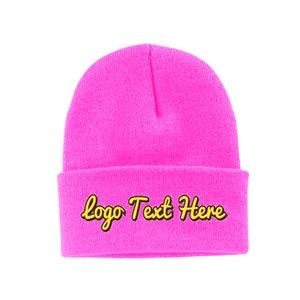 May include: A bright pink beanie with a yellow embroidered logo that says "logo Text Here".
