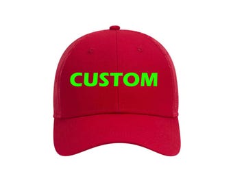May include: A red baseball cap with a mesh back and a curved brim. The word "CUSTOM" is printed in bright green across the front of the cap. The cap has a button on top.
