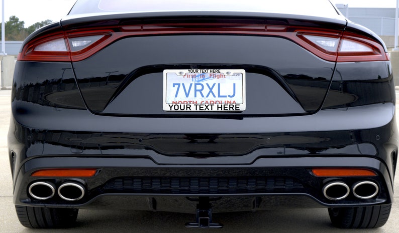May include: Black car with a personalised number plate that reads "7VRXLJ" and the text "YOUR TEXT HERE" above and below the plate. The number plate also has the text "First to Flight" and "NORTH CAROLINA" on it.