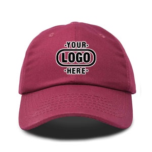 May include: A burgundy baseball cap with a white oval containing the text "YOUR LOGO HERE" in black.