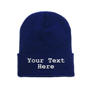 May include: A navy blue beanie hat with a folded brim. The text "Your Text Here" is printed in white on the folded brim. The hat is made of a soft, knitted material.