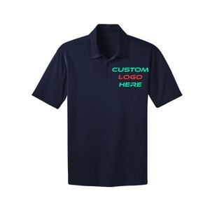 Puede incluir: Una camiseta polo azul marino con un logotipo personalizado bordado en el pecho. El logotipo dice "CUSTOM LOGO HERE" en verde y rojo.