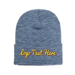 May include: A blue beanie with the text "Logo Text Here" in yellow and maroon script. The hat is made of a soft, knitted material and is designed to be worn on the head. This winter hat is a great accessory.