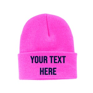 May include: A bright pink beanie with the text "YOUR TEXT HERE" in black.