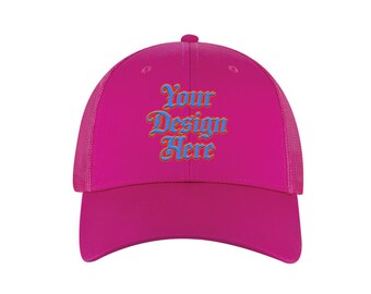 May include: A magenta trucker hat with a curved brim and mesh back. The front panel displays the text "Your Design Here" in a stylized blue and orange font. The hat has a button on top.