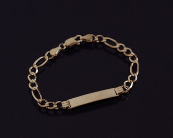 May include: A gold-toned metal bracelet featuring a series of oval and circular links connected to a central rectangular identification plate. The bracelet includes a lobster claw clasp mechanism for securing the piece around the wrist.