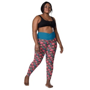 May include: A pair of black leggings with a floral print and a teal waistband. The leggings are made of a stretchy material and have a high waist.