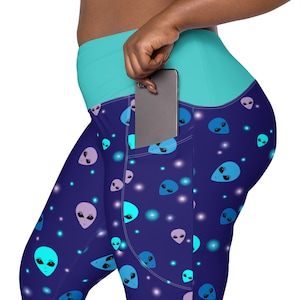 May include: Blue and purple leggings with a pattern of alien faces and white dots. The leggings have a turquoise waistband and a phone pocket on the right side.