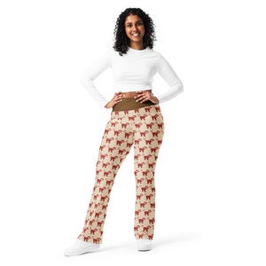 May include: A woman is wearing brown and beige leggings with a red monkey pattern. The leggings are fitted and have a high waist. The woman is wearing a white long-sleeved shirt.