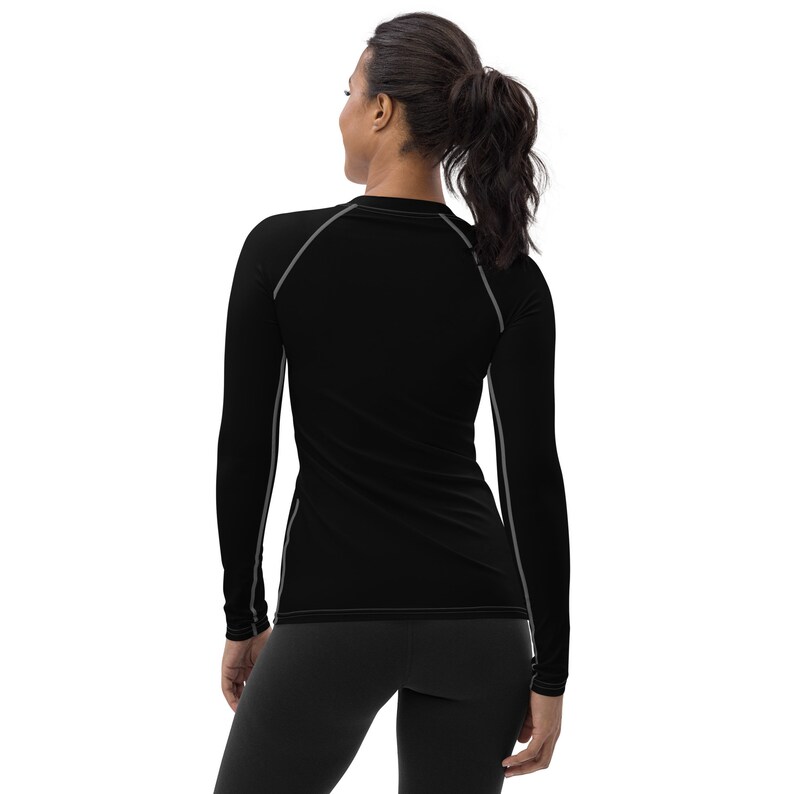 May include: Black long-sleeve shirt with gray trim around the neckline and sleeves. The shirt is fitted and has a crew neck.